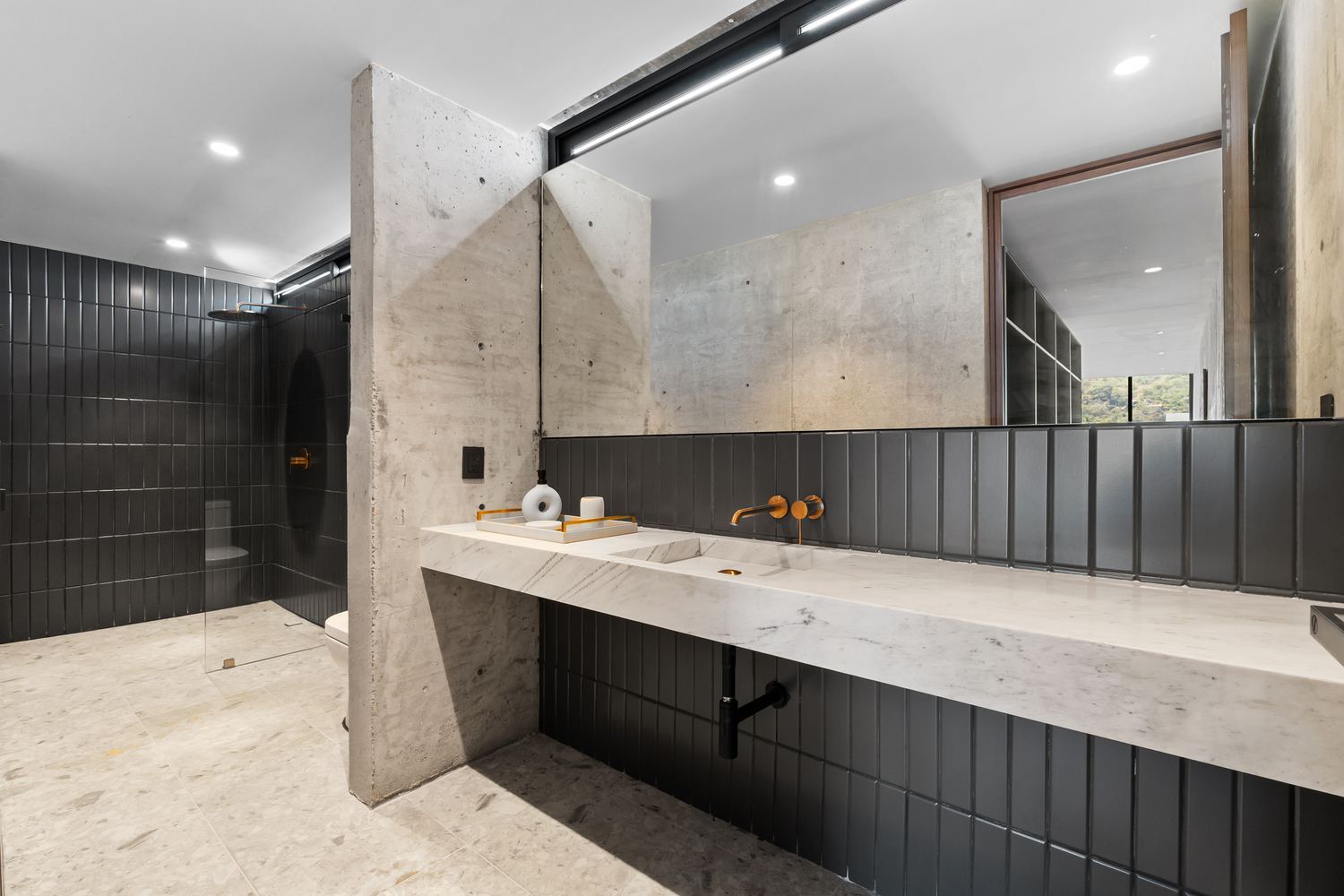Floating marble vanity and walk-in shower bathed in light
