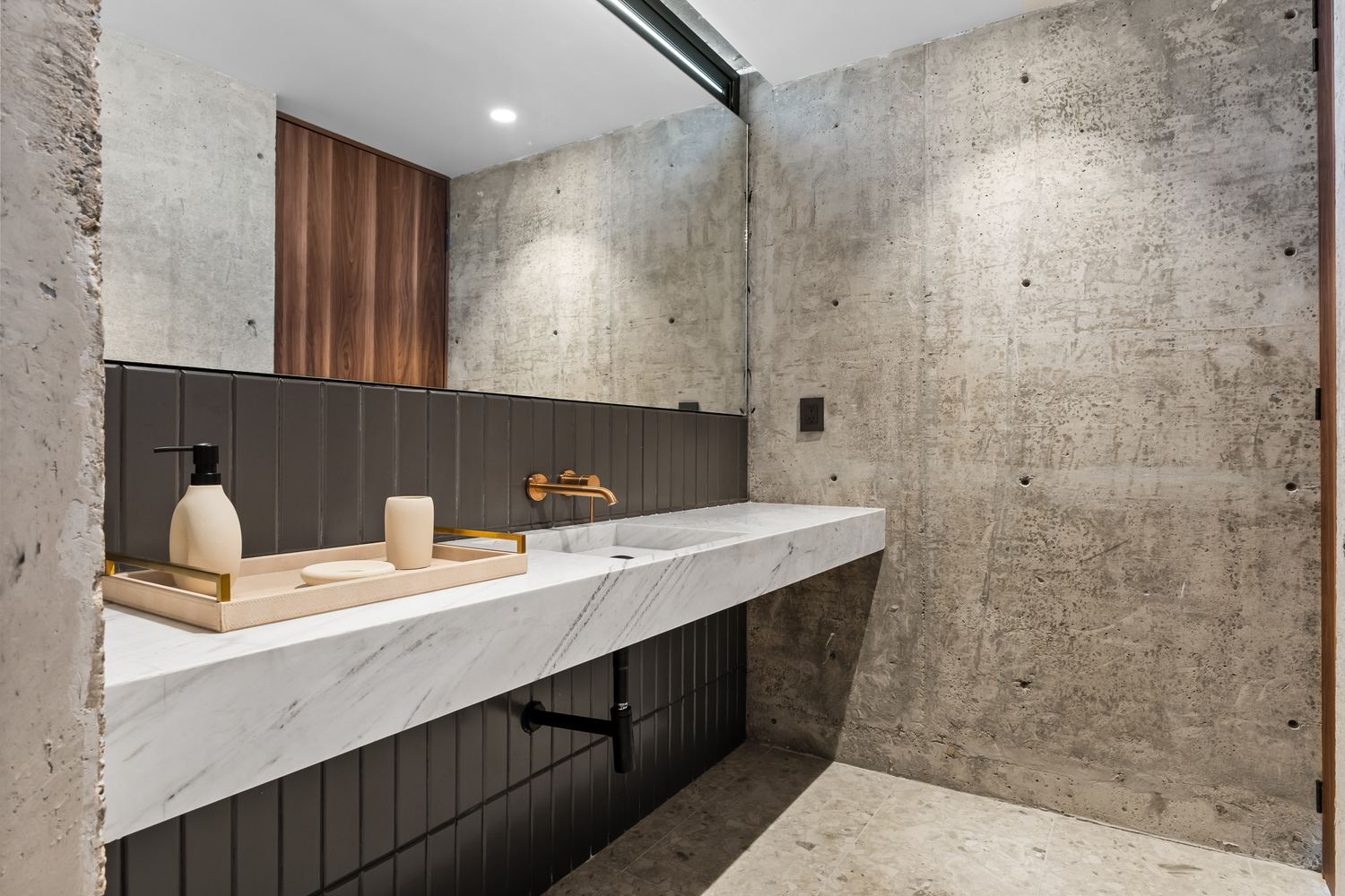 Detail of marble counter, warm brass tap and wood cabinetry