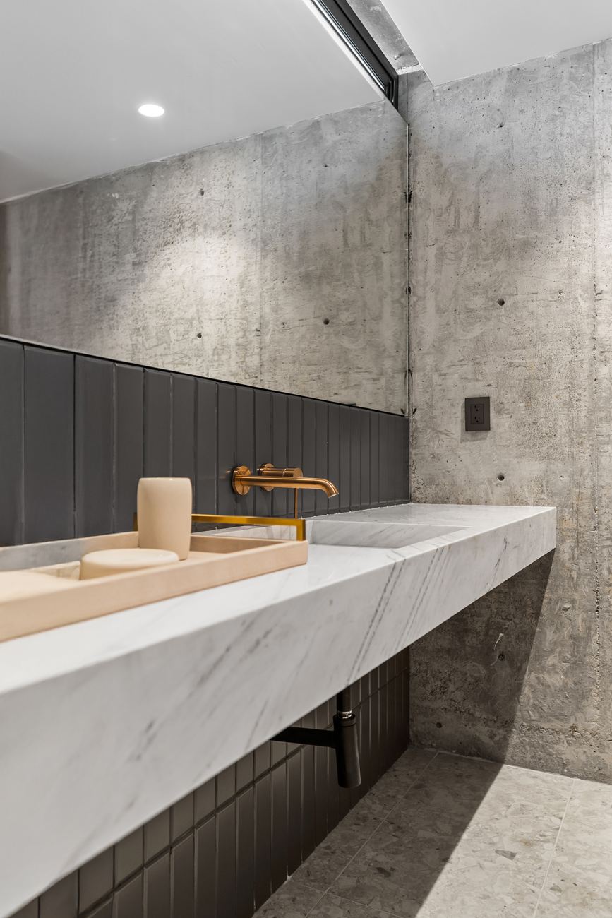 Honed marble vanity with warm brass fixtures in soft light